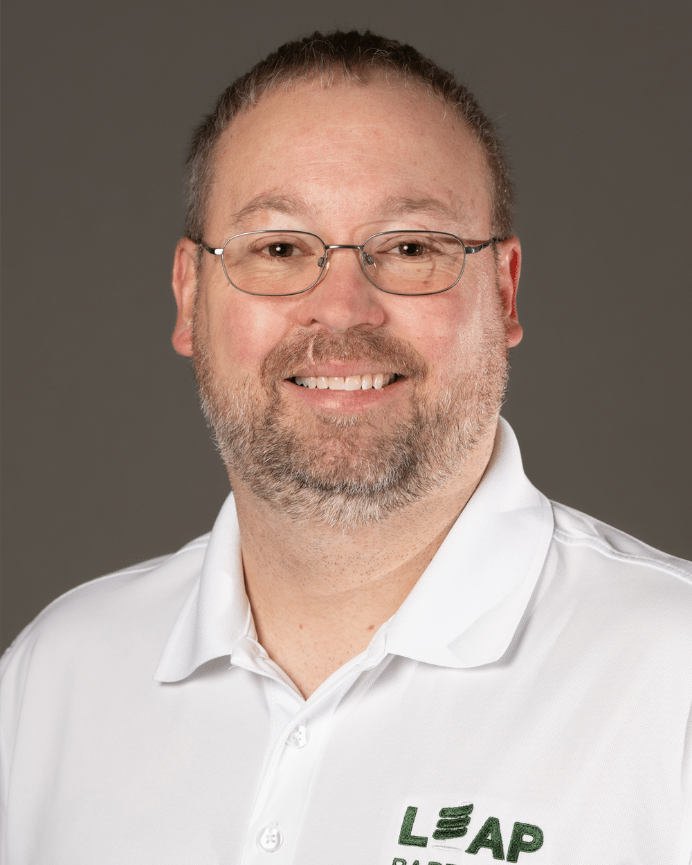 a man wearing glasses and smiling at the camera