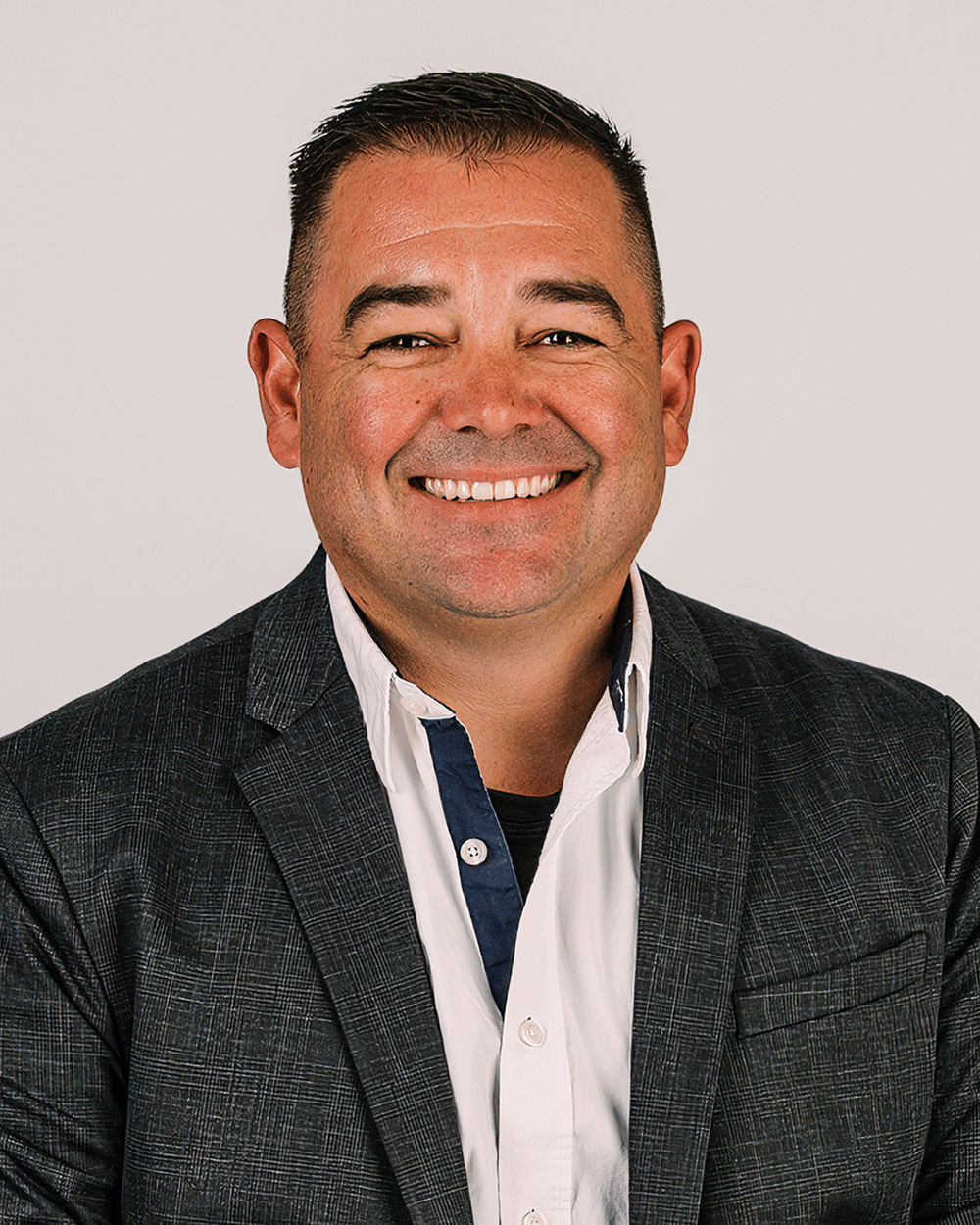 a man wearing a suit and tie smiling at the camera